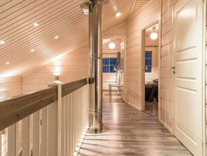 A wooden interior with a sloped ceiling, a central metal column, and a staircase leading to a bedroom. - Levin ahmahovi 1a by Interhome (Kittilä)