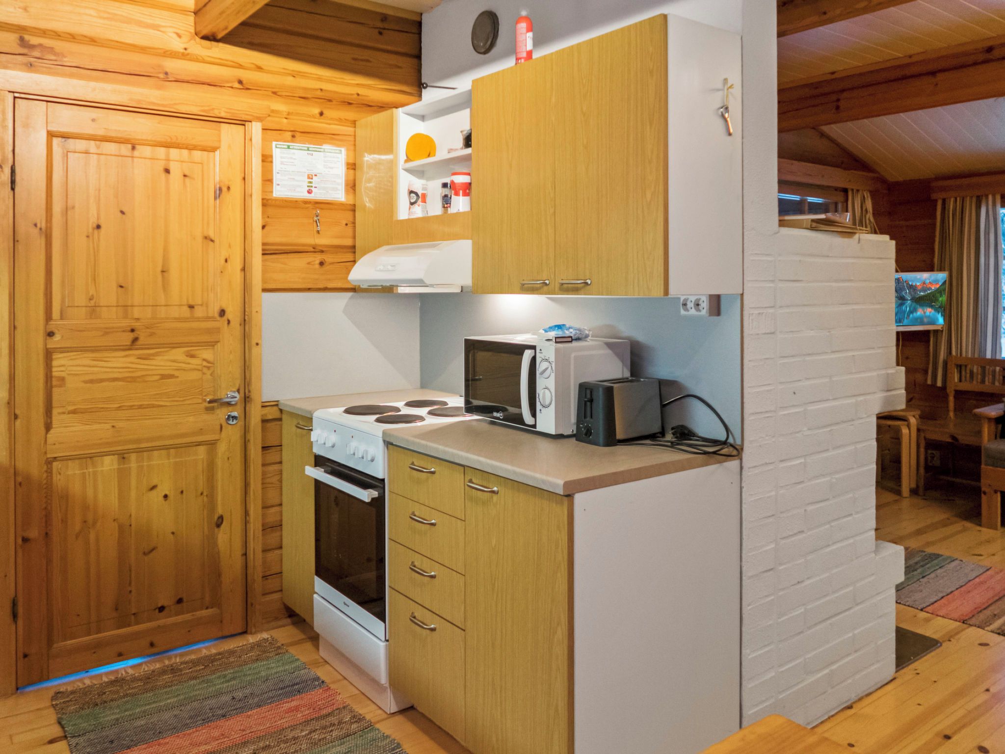 Una cocina compacta con armarios de madera, estufa, microondas y un refrigerador pequeño.