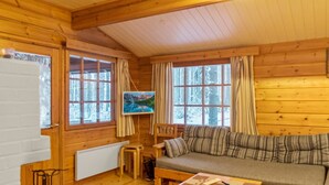 A cozy cabin interior with a wooden floor, a sofa, a small table, and a painting on the wall. - Kanerva by Interhome (Sotkamo)