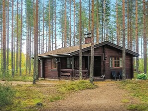 A rustic cabin with a porch, surrounded by tall trees. - Kanerva by Interhome (Sotkamo)