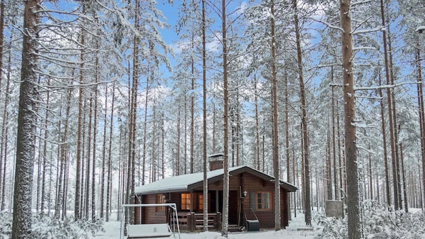 A wooden cabin surrounded by tall, snow-covered trees. - Kanerva by Interhome (Sotkamo)