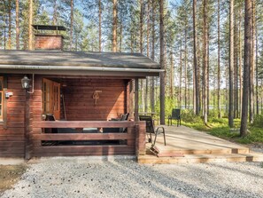 A wooden cabin with a porch, a chimney, and a gravel driveway leading to a dock. - Kanerva by Interhome (Sotkamo)