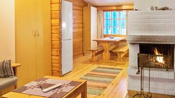 L’intérieur chaleureux d’un chalet avec une table à manger en bois, une cheminée et un coin cuisine.
