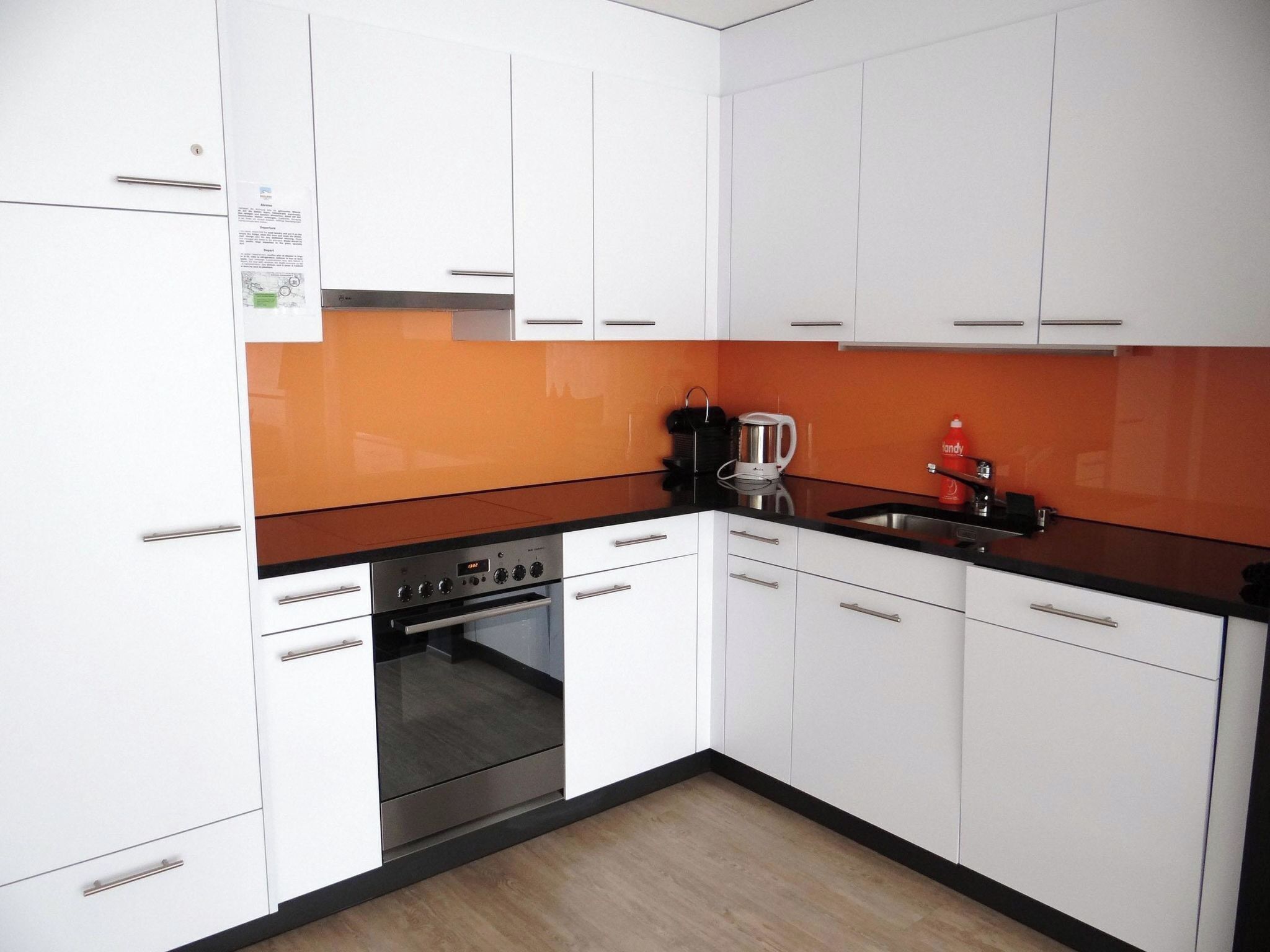 Een keuken met witte kasten, een zwart aanrecht en een oven van roestvrij staal.