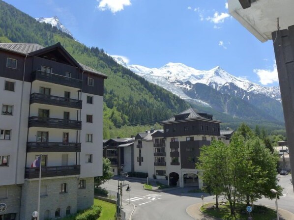 A hotel with multiple floors, balconies, and a view of snow-capped mountains.