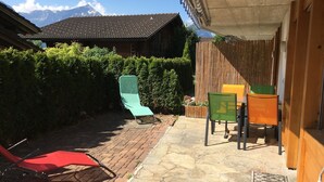 Une terrasse avec des sièges extérieurs, un bâtiment en bois et une vue sur la montagne.