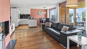Un salon moderne avec un canapé noir, une table basse blanche et une cheminée.