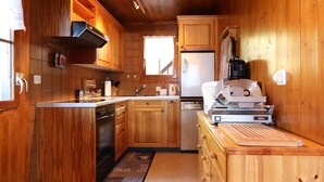 Una cucina in legno con isola centrale, forno a incasso e frigorifero.