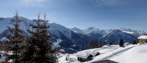 A snow-covered mountain landscape with a wooden deck in the foreground.