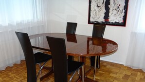 Un comedor con una mesa redonda y cuatro sillas, piso de parqué de madera y un cuadro en la pared.