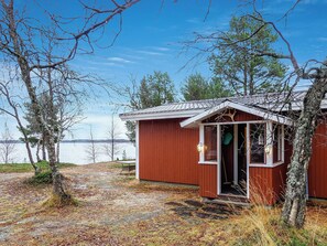 A small wooden cabin with a door open, situated near a body of water with trees around. - Mellaniemi by Interhome (Inari)