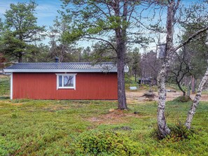 A red wooden cabin with a window, surrounded by trees and grassy ground. - Mellaniemi by Interhome (Inari)