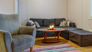 Ein gemütliches Wohnzimmer mit einem grauen Sofa, einem Holztisch mit Kerzen und einem farbenfrohen Teppich.