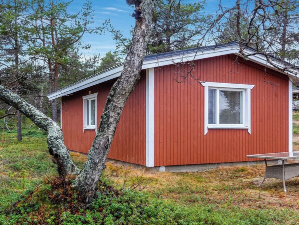 A red wooden cabin with a single window and a door, surrounded by trees and grass. - Mellaniemi by Interhome (Inari)