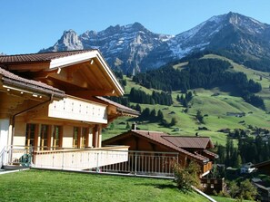 Un edificio de estilo chalet con balcón y vistas a un paisaje montañoso.