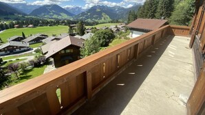 A balcony with a view of a mountain village and a wooden fence.