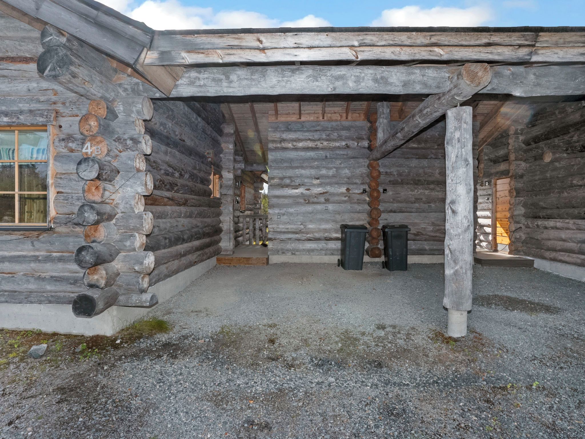 A log cabin with a gravel ground, a window, and a door.