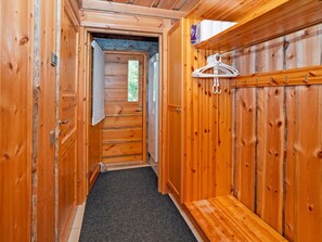Un pasillo de madera con una puerta que da a una habitación, un perchero y una pequeña mesa.