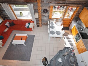 A modern living room with a red sofa, a white coffee table, and a dining area with a white table and chairs.