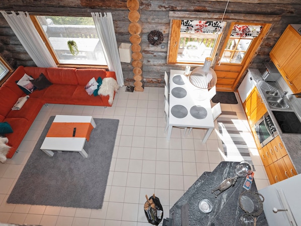 Un salon moderne avec un canapé rouge, une table basse blanche et un coin repas comprenant une table et des chaises blanches.