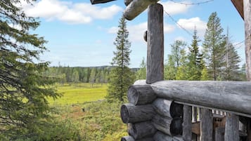 A log cabin with a view of a forest and open field.