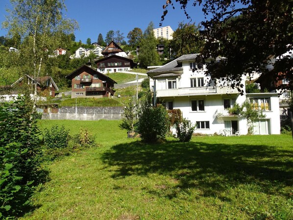 Ett bostadsområde med hus, en gräsyta och träd.