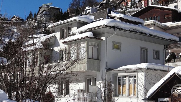 Un bâtiment enneigé, doté de nombreux balcons, sous un ciel dégagé.