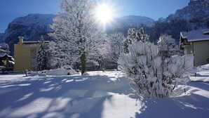 Un paysage enneigé, avec une montagne en arrière-plan et un bâtiment à la façade jaune.