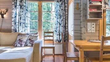 L’intérieur d’un chalet chaleureux, avec un canapé, une table à manger en bois et une chaise.