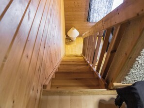 A wooden staircase with a handrail, leading to a room with a light fixture.