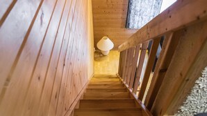 Un escalier en bois, doté d’une rampe et d’un luminaire fixé au mur.