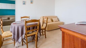 Un comedor con una mesa dispuesta para dos, sillas de madera y un sofá al fondo.