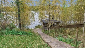 A wooden boardwalk leading to a gazebo in a wooded area.
