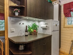 Une cuisine compacte équipée d’un réfrigérateur intégré, d’un évier et d’un plan de travail agrémenté d’une plante en pot et d’une bouteille de vin.