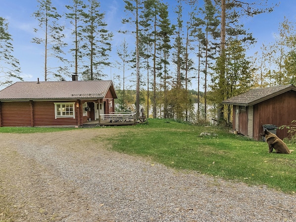 A cabin with a gravel driveway, a wooden deck, and a dog in the foreground. - Kytöranta by Interhome (Hartola)