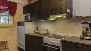 A compact kitchen with dark cabinetry, a microwave, a stove, and a sink.