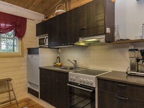Una cocina compacta con armarios oscuros, un microondas, una estufa y un lavamanos.
