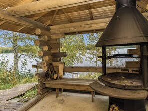A rustic outdoor seating area with a wood-burning stove and logs stacked nearby. - Kytöranta by Interhome (Hartola)