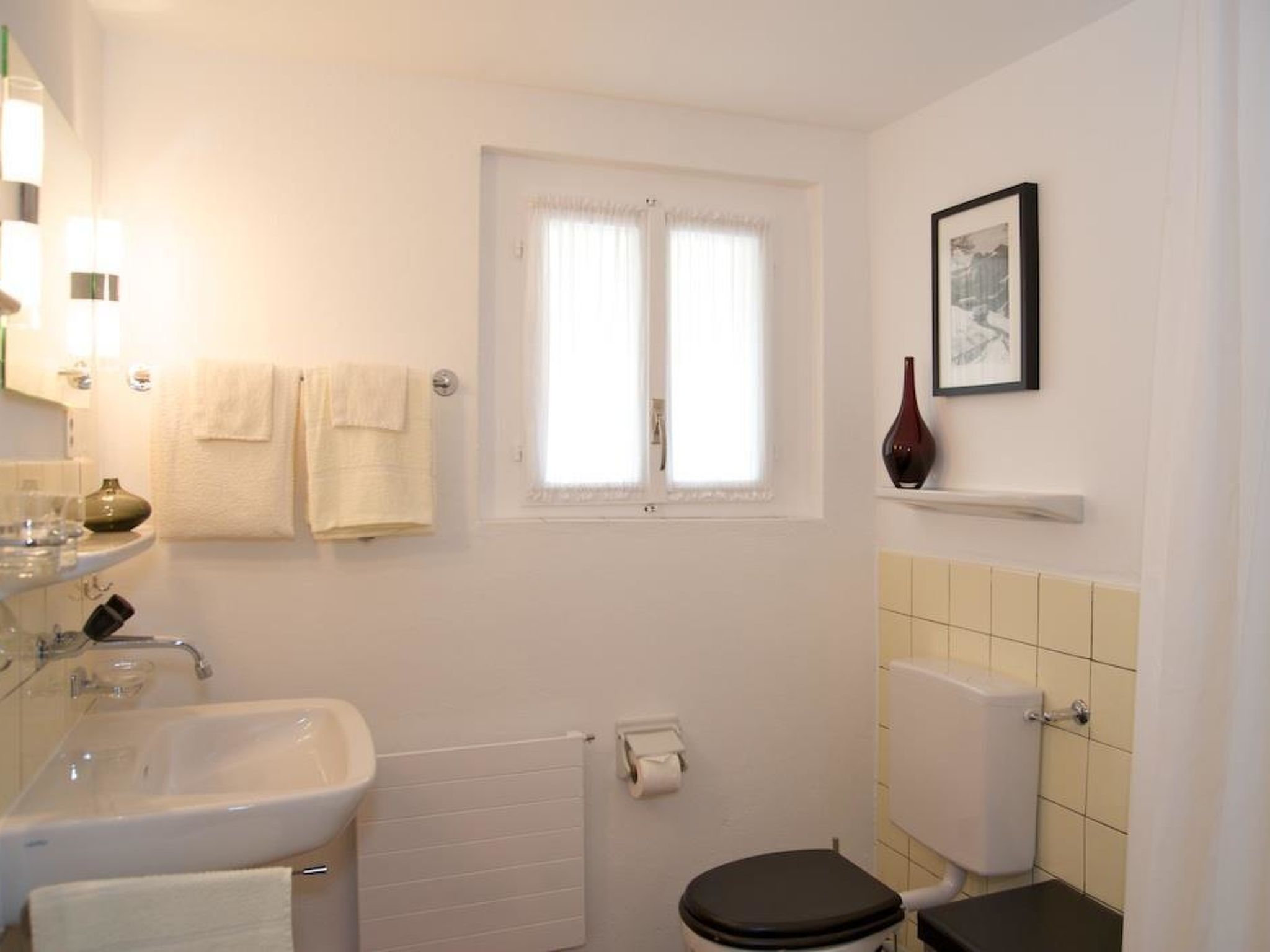 Ein kleines Badezimmer mit Waschbecken, Toilette und Fenster.