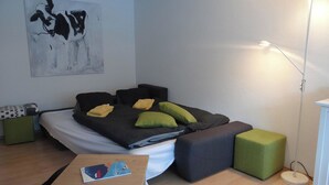 A modern bedroom with a bed, pillows, a bedside table, a floor lamp, and a painting on the wall. - Neuschwändi 63 Appartement/Fewo 4-Bettwohnung by Interhome (Engelberg)
