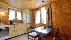 A wooden cabin interior with a kitchen, dining table, and chairs. - Apartment Maria by Interhome (Saas-Fee)