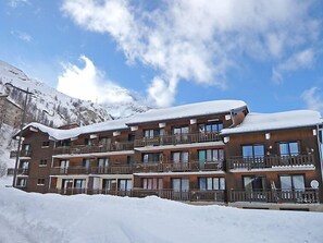 Ein mehrstöckiges Hotel mit Balkonen vor einer verschneiten Berglandschaft.