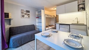 A compact kitchen with a dining table set for two, a built-in oven, and a microwave. - Les Olympiques (Tignes 1800) by Interhome (Tignes)