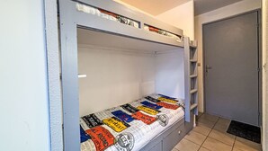 A bunk bed with a travel-themed mattress cover, a door to the right, and a tiled floor. - Les Olympiques (Tignes 1800) by Interhome (Tignes)