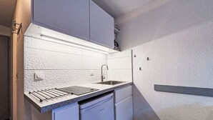 A compact kitchen with white cabinetry, a stainless steel sink, and a built-in oven. - Les Olympiques (Tignes 1800) by Interhome (Tignes)