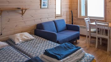 A cabin-style room with a sofa, two beds, a table, and chairs.