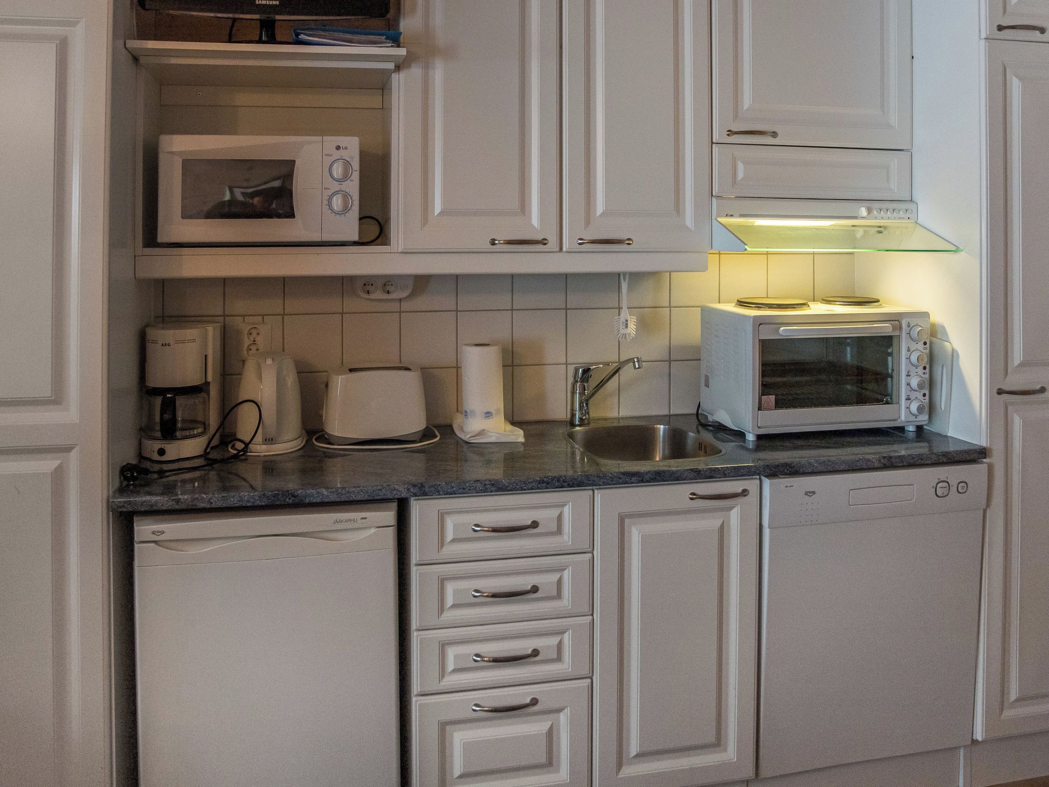 A kitchen with white cabinets, a microwave, a toaster, and a dishwasher.