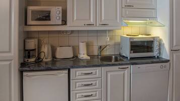 A kitchen with white cabinets, a microwave, a toaster, and a dishwasher.