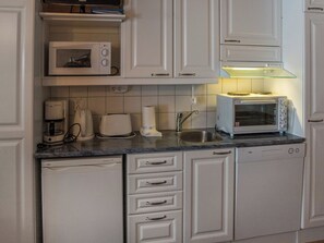 A kitchen with white cabinets, a microwave, a toaster, and a dishwasher. - Vaeltajankulma huoneisto 3 by Interhome (Ylläsjärvi)