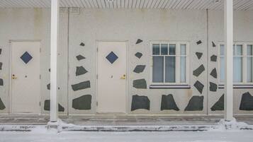 A building with two doors, each with a diamond-shaped window, and a window with horizontal blinds.